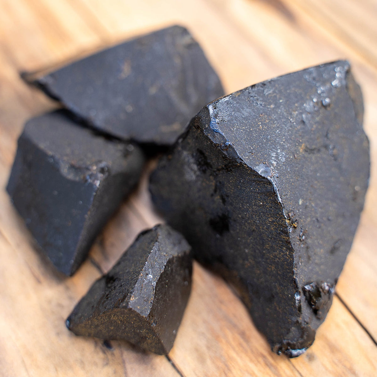 Pieces of dark labdanum resin on a wooden surface