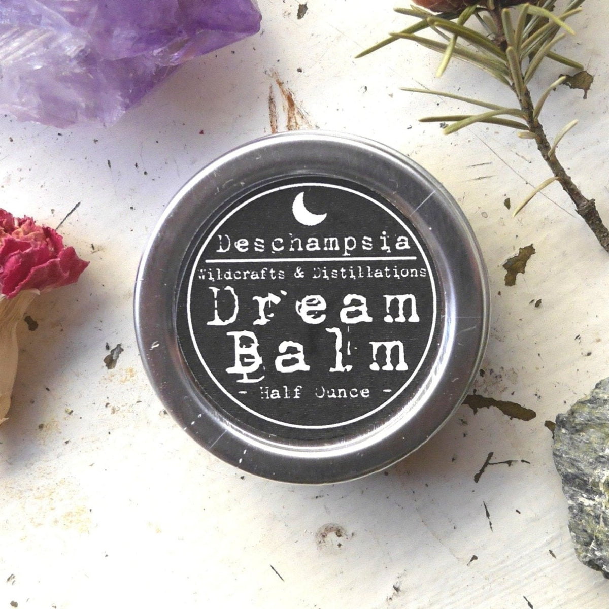 Dream Balm tin surrounded by dried rose, evergreen, crystals, and botanical materials