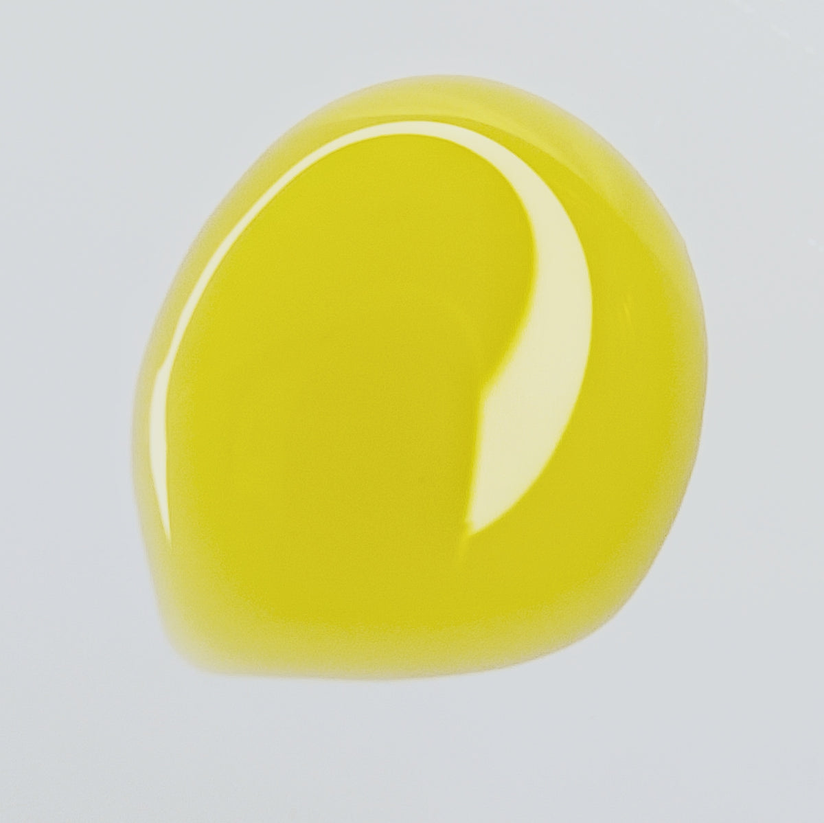 Golden Glow Serum facial oil pooled on a pale surface, showing its color and texture.