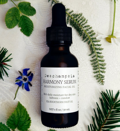 Deschampsia Harmony Serum 30 mL bottle with blue flowers, green leaves, fern and evergreen sprigs on cream fabric.